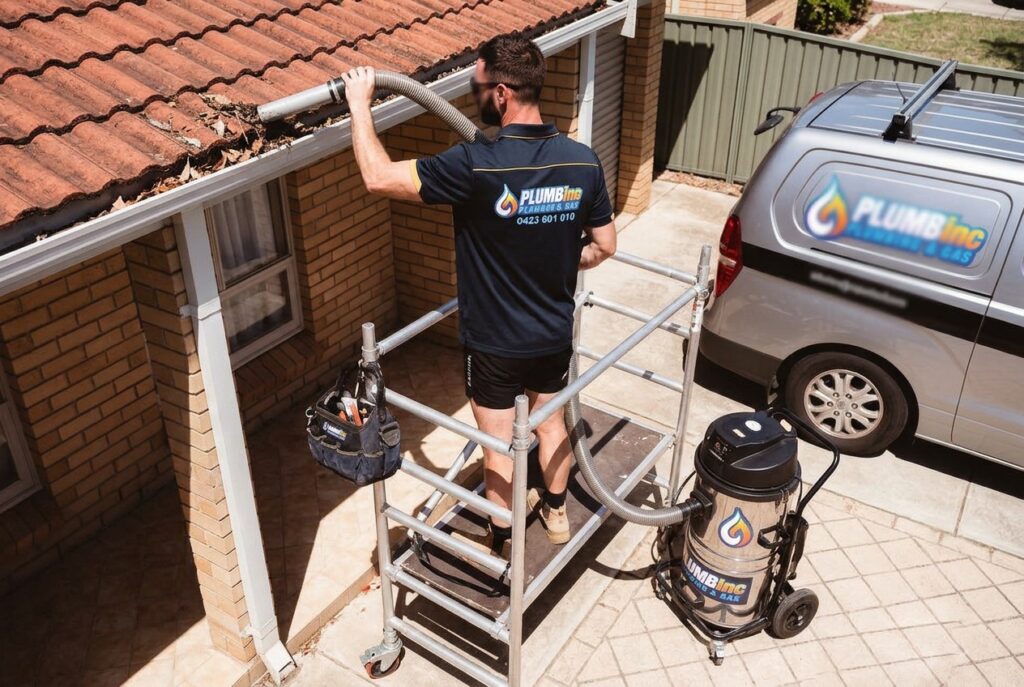 Plumber on scaffold performing a residential homes gutter cleaning